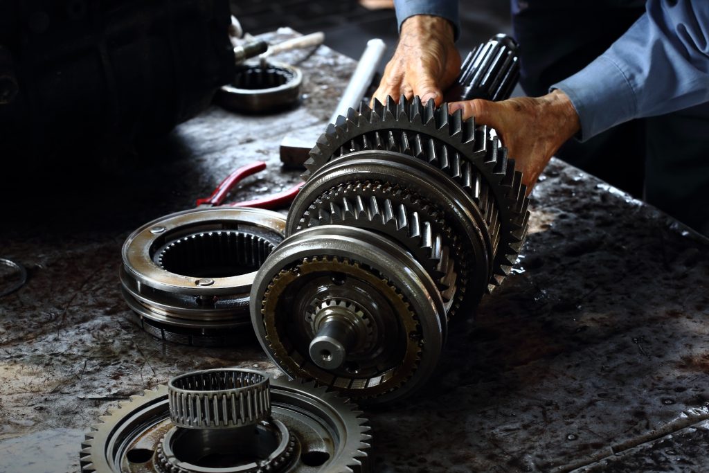 An image of a disassembled car transmission being serviced. 