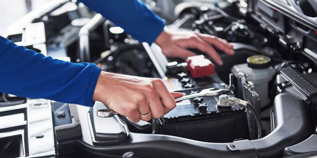 A closeup of a service technician performing regular maintenance on a car engine.